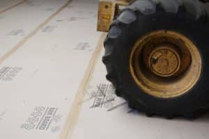wheel of forklift driving over ram board floor protection