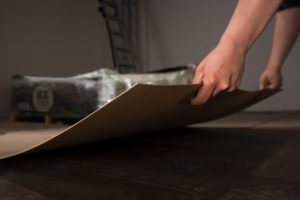 a person holding the edge of a pro sheet, paperboard floor protection