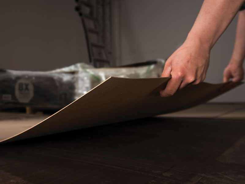 a person holding the edge of a pro sheet, paperboard floor protection