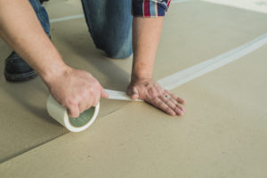 Vapor cure seam tape being applied to surface protection