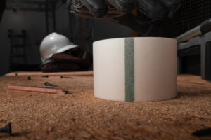foreground close up of white vapor cure seam tape with a pencil, screws, and a hard hat in the background