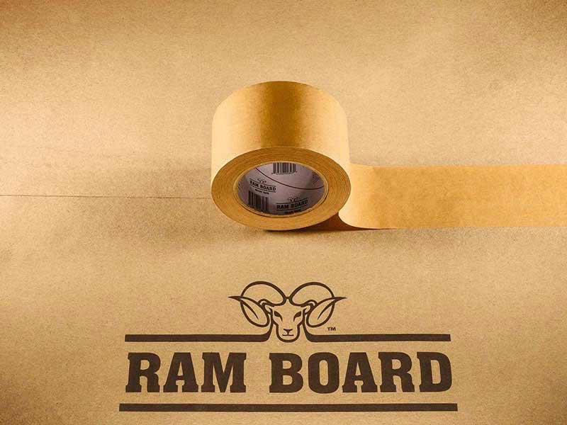a roll of brown ram board seam tape sitting on two sheets of ram board floor protection