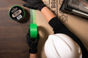 ram board green adhesive tape applied to surface protection and floor by construction worker
