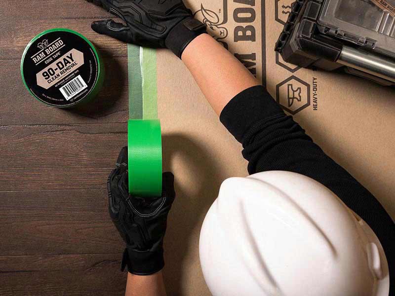 ram board green adhesive tape applied to surface protection and floor by construction worker