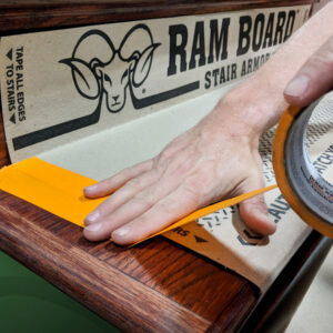 orange edge tape being applied to ram board stair protection