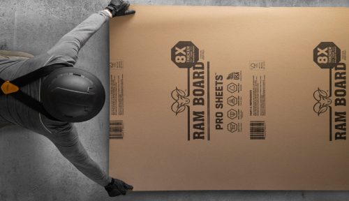 Ram Board Pro листовая защита пола, уложенная на цементный пол человеком в каске и перчатках